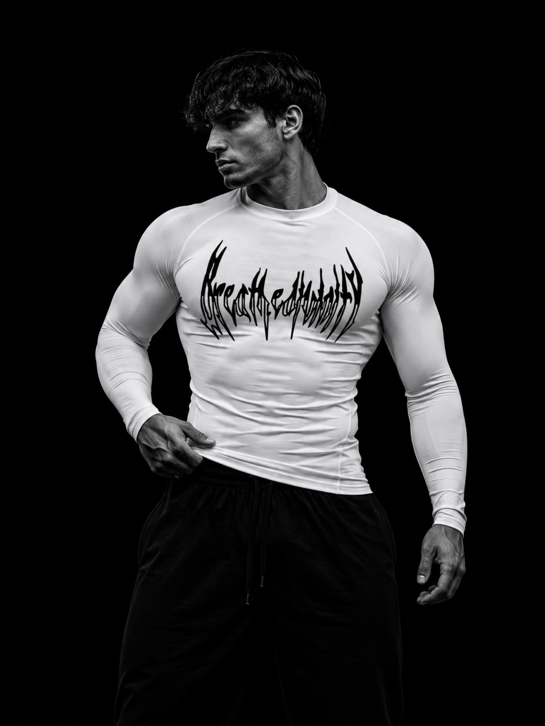 Homme musclé portant le t-shirt de compression manches longues Breathedivinity blanc, imprimé noir, vue de trois-quarts studio.